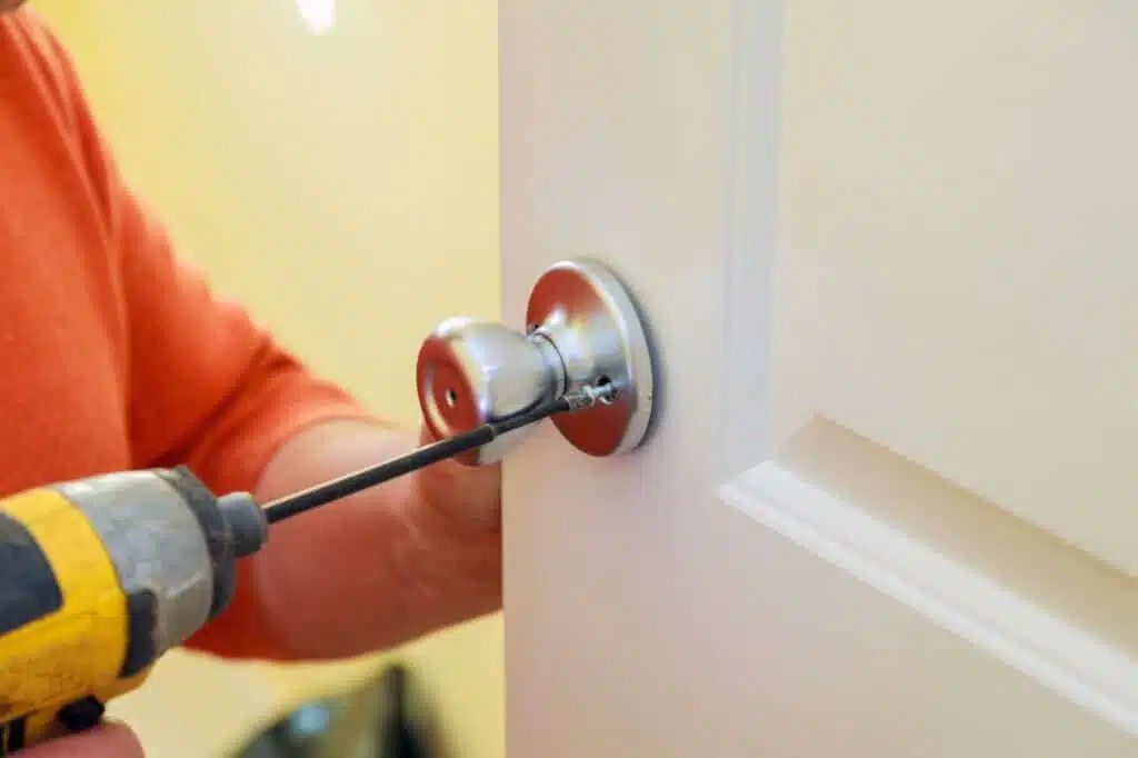 Handyman repair worker's hands installing new door locker man repairing the doorknob. closeup