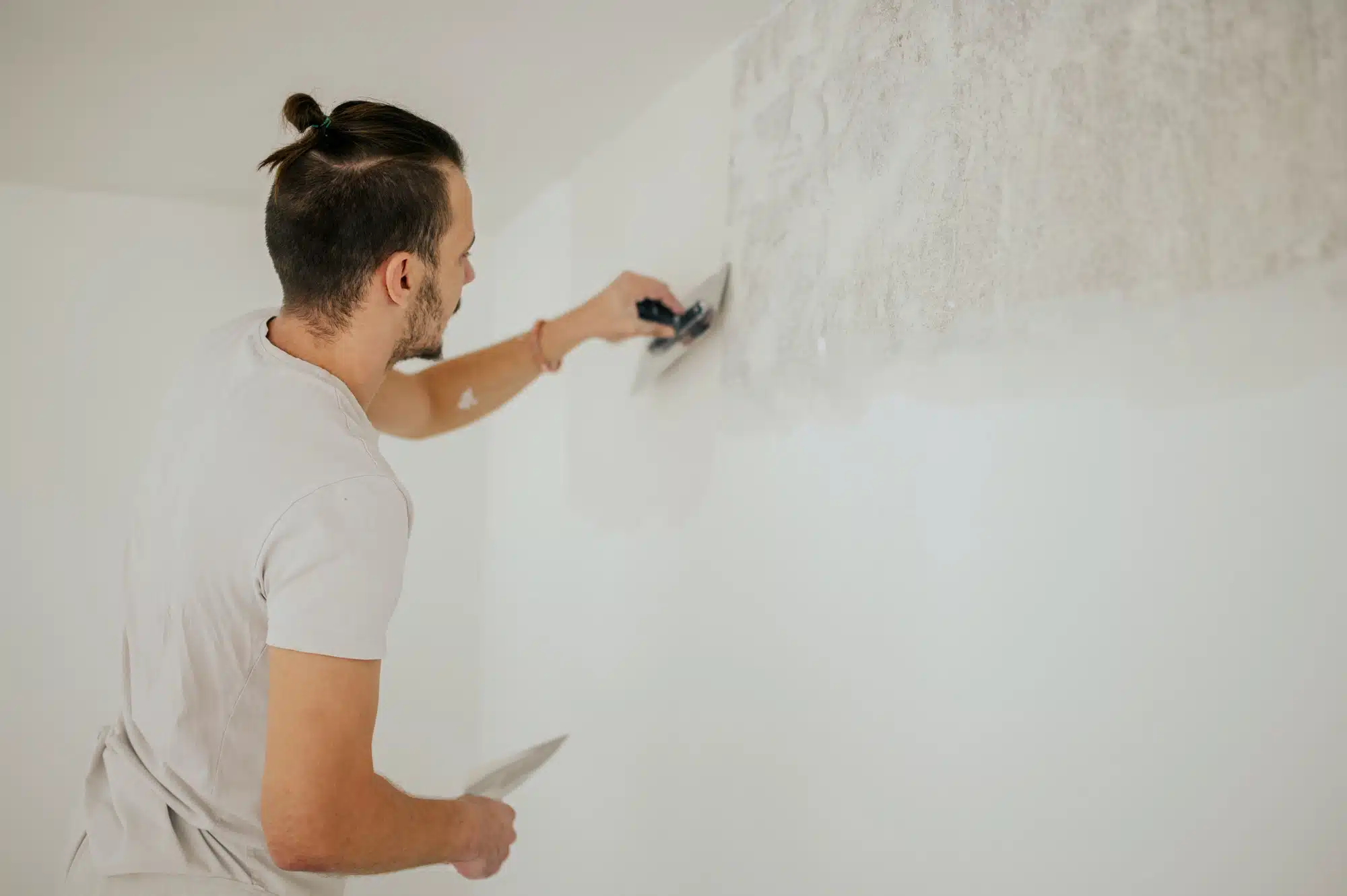 A plasterer is using tools for skim coating walls.